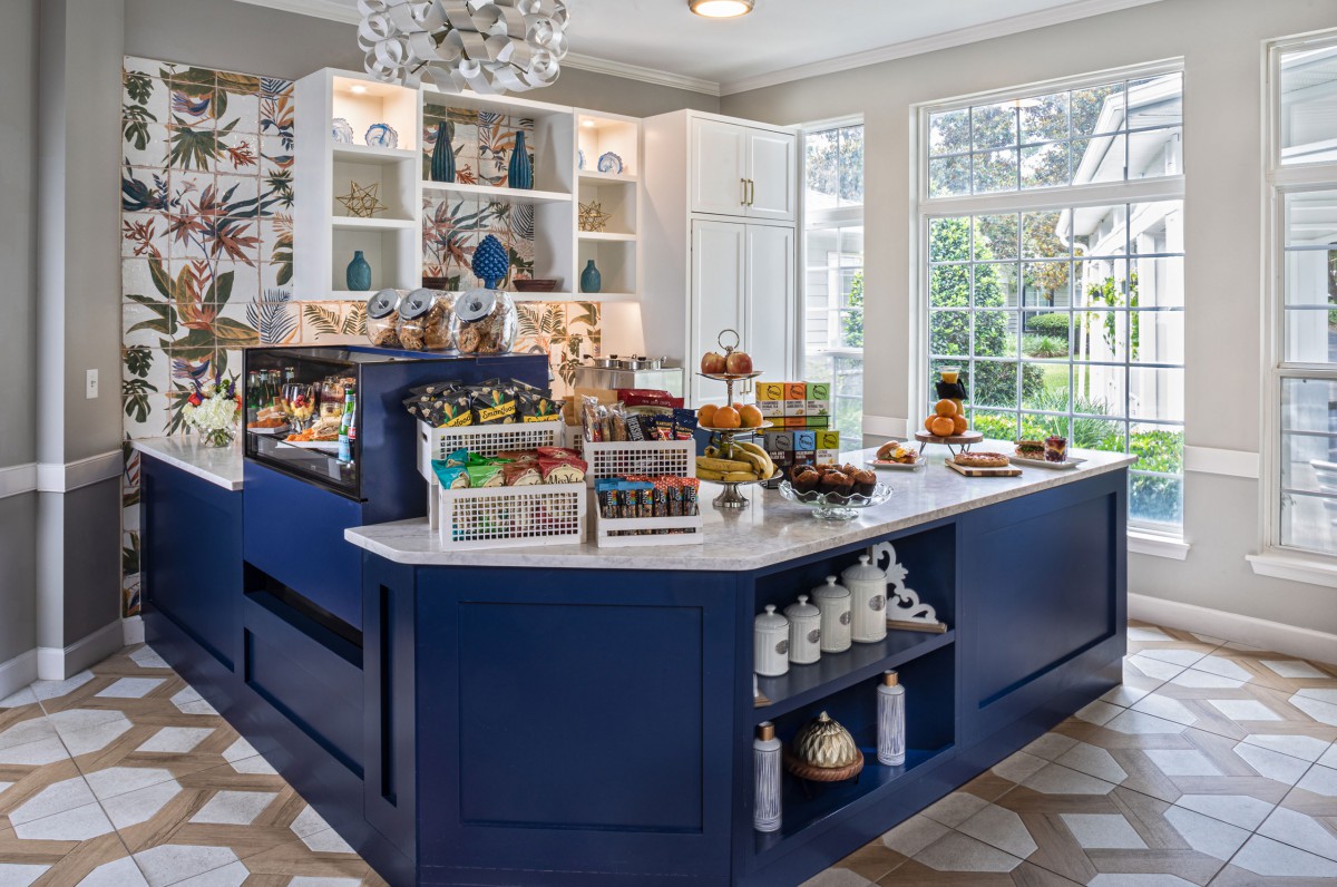 A quaint cafe interior featuring a central blue counter displaying an assortment of desserts and snacks.