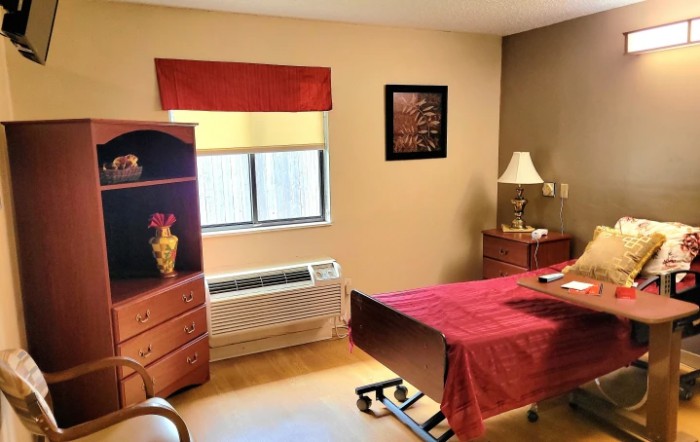 A cozy bedroom with a single bed, dresser, and lamp.