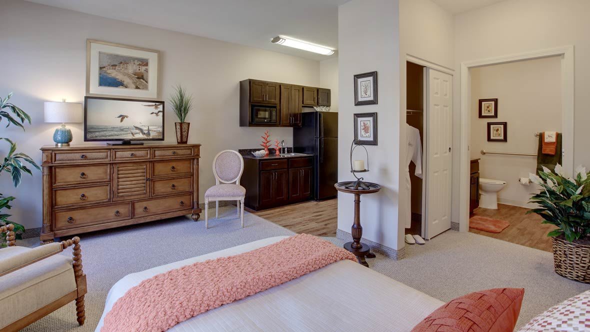 A cozy apartment with a bedroom and kitchenette area, featuring elegant furniture and decor.