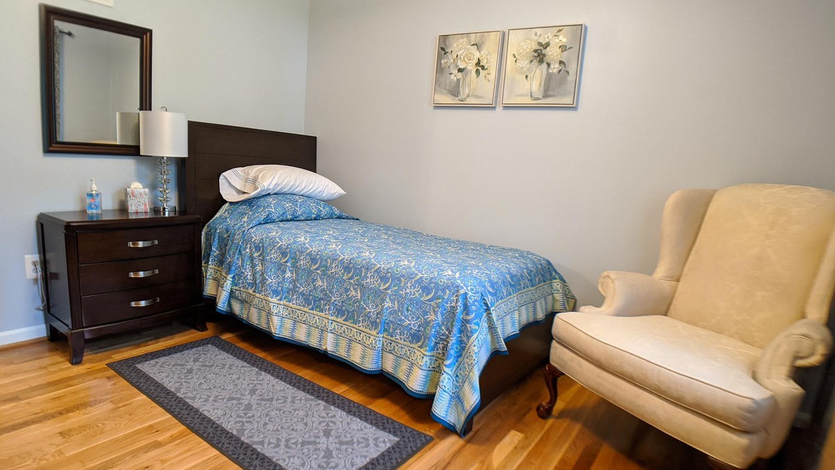 A cozy bedroom with a single bed covered in blue bedding, featuring modern decor and artwork on the walls.