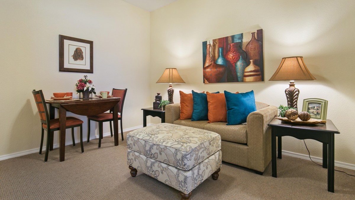A cozy living room with a sofa, colorful cushions, and decorative artwork.