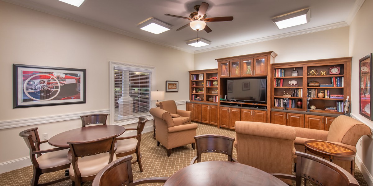 A cozy living room with armchairs, a television, and bookshelves.