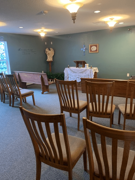 A small chapel with wooden chairs facing an altar, creating a peaceful and intimate worship space.
