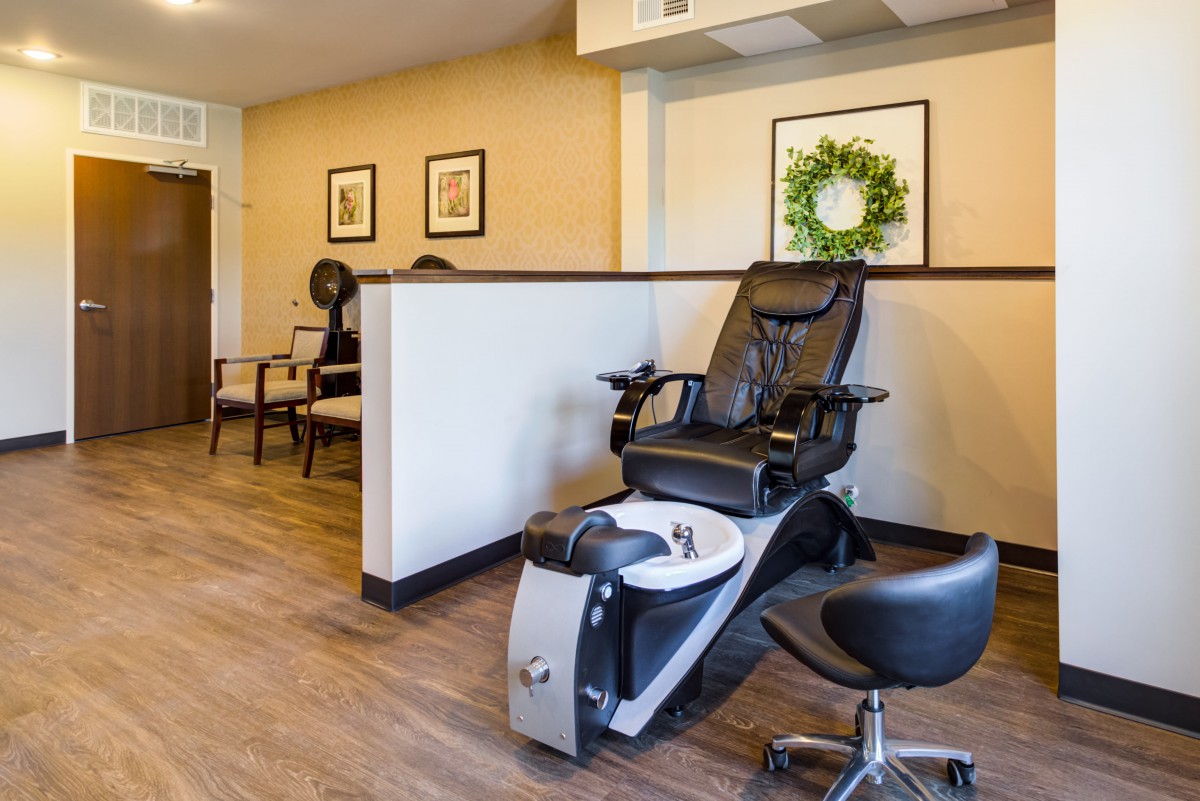 A salon interior featuring a pedicure chair and a cozy waiting area.