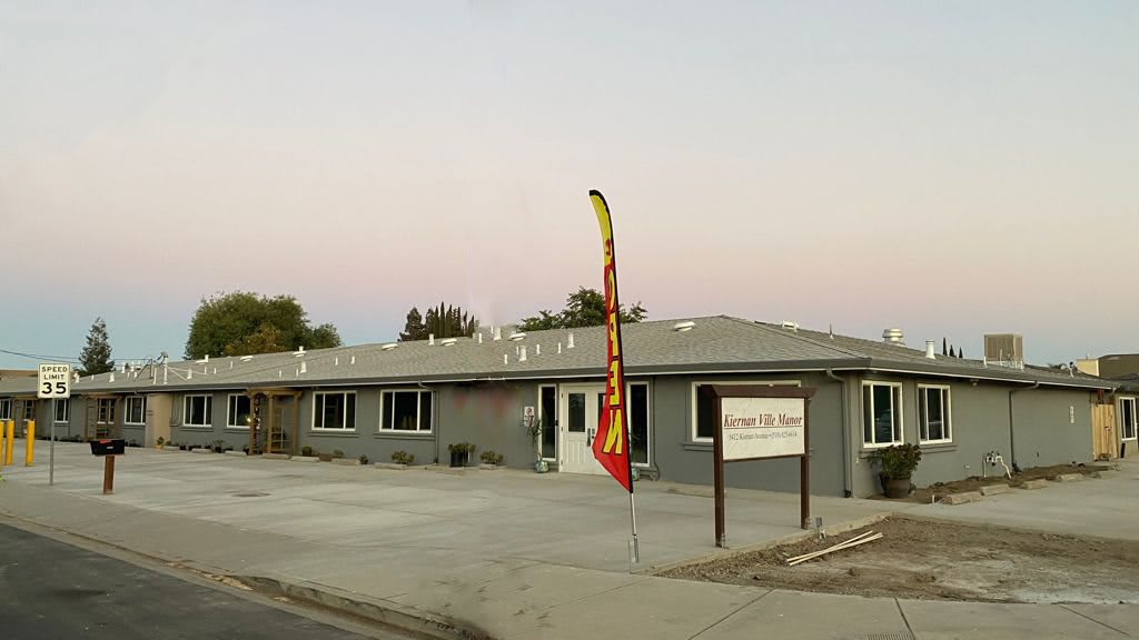 A commercial building with a sign and flag at sunset.