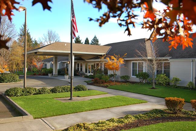 A well-maintained building surrounded by autumn foliage, featuring a flagpole and a neatly landscaped garden.