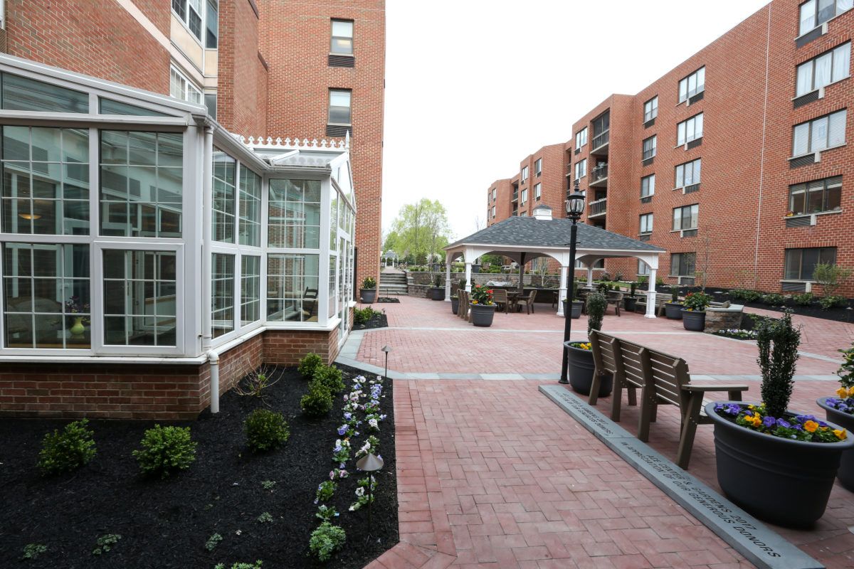 A well-maintained courtyard between apartment buildings featuring brick pathways and outdoor seating.