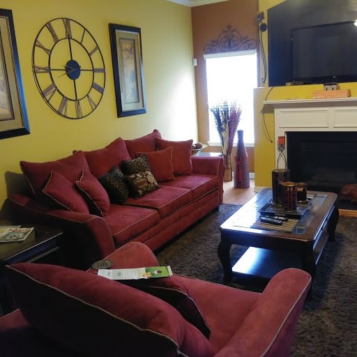 A cozy living room featuring red sofas, yellow walls, a fireplace, and a flat-screen TV.
