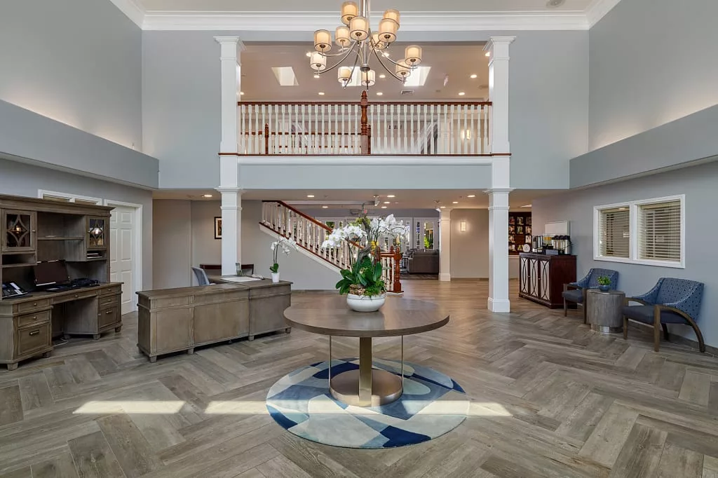 A luxurious interior foyer featuring a grand chandelier, elegant staircase, and stylish furniture.