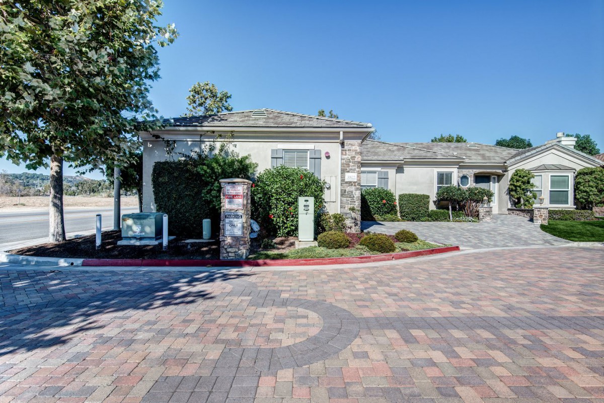 A suburban house with a well-maintained driveway and landscaping under a clear blue sky.
