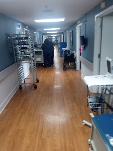 A corridor in a healthcare facility, featuring medical equipment and staff attending to patients.