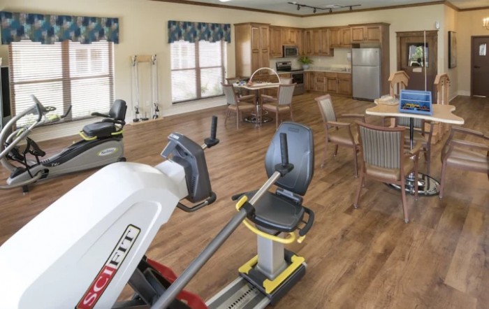 A multifunctional room with fitness equipment and a kitchen area.