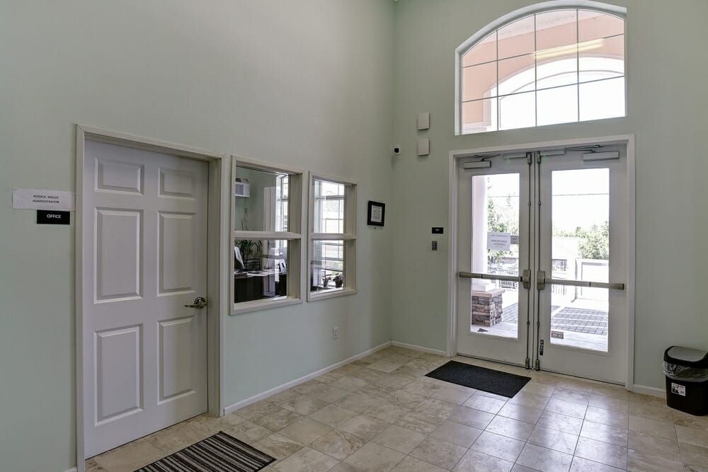 A lobby entrance with tiled flooring and double glass doors.
