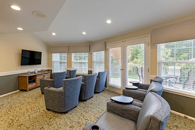 A cozy living room with multiple armchairs, a television, and large windows.