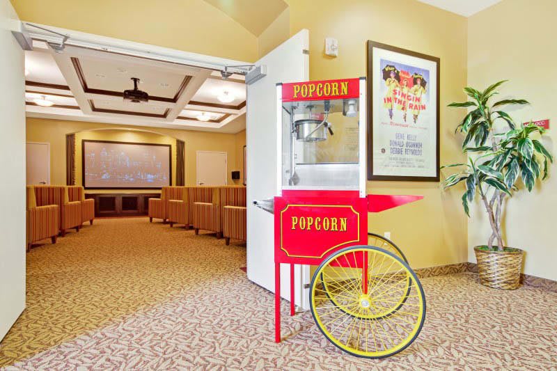 A home theater room featuring a classic red popcorn machine and comfortable seating.