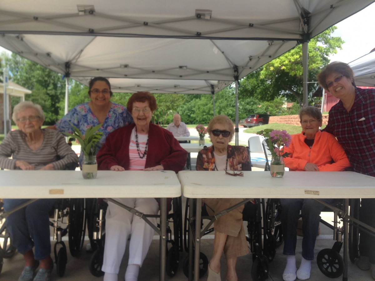 A group of elderly individuals sitting under a tent outdoors.