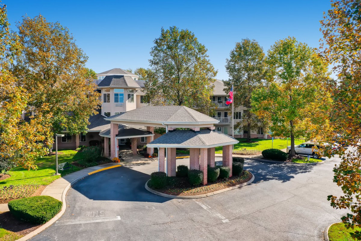 Aerial view of a building with a covered entrance and surrounding trees.