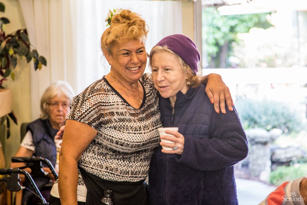 Two people hugging and smiling indoors, enjoying a moment together.