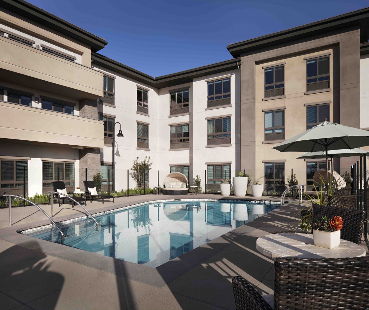 A modern apartment complex featuring an outdoor swimming pool and patio area.