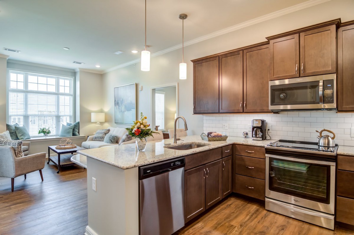 A modern open-concept kitchen with wood cabinets and stainless steel appliances, seamlessly connected to the living area.