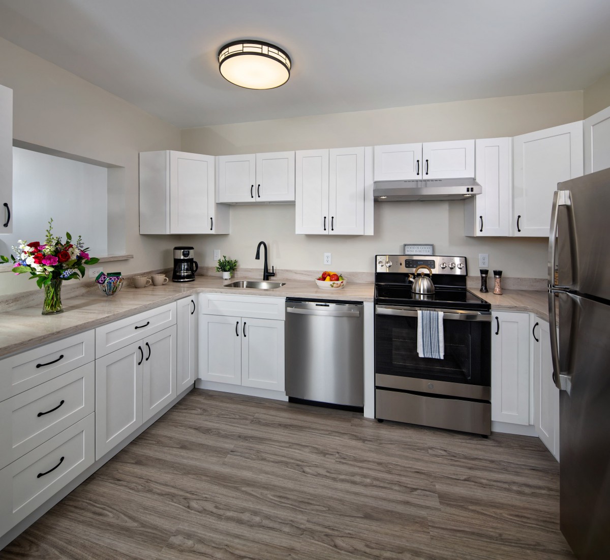 A modern kitchen with white cabinets and stainless steel appliances.