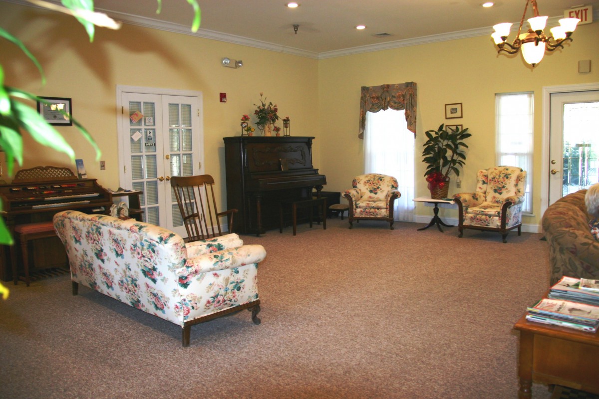 A cozy living room with floral-patterned furniture and a piano.