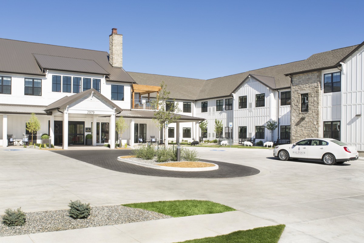 A modern residential building with a circular driveway and landscaped areas.