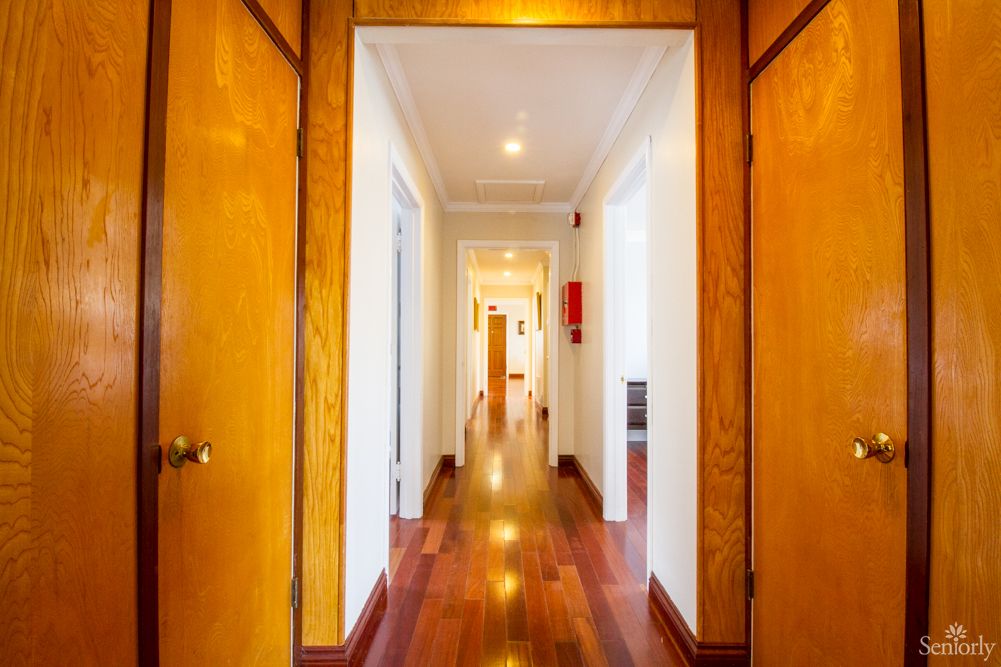 A brightly lit hallway with wooden floors and multiple doors.