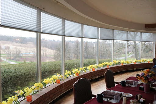 A serene dining area with large windows offering a view of the outdoors, adorned with colorful flowers along the curved ledge.