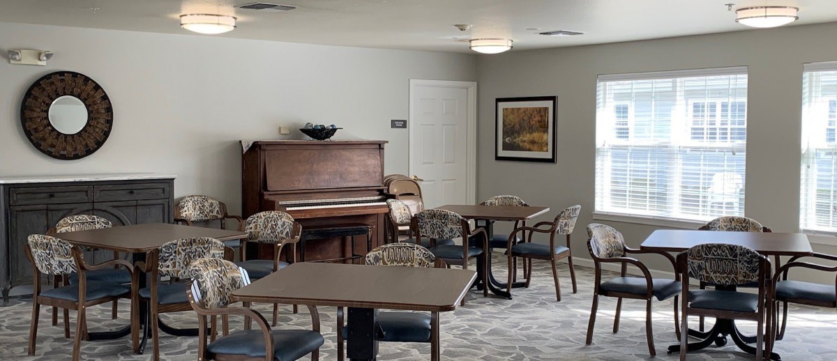 A cozy room with a piano, tables, and chairs for relaxation or gatherings.