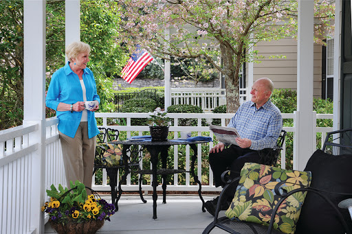 A cheerful conversation on a sunny porch with an American flag in the background.