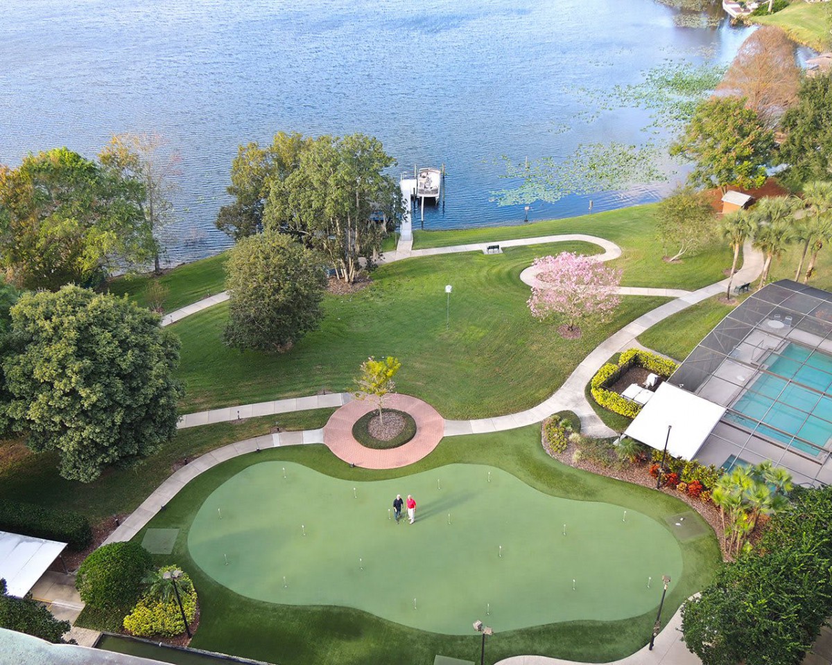 Aerial view of a scenic golf course by a tranquil lake, surrounded by lush greenery and winding pathways.
