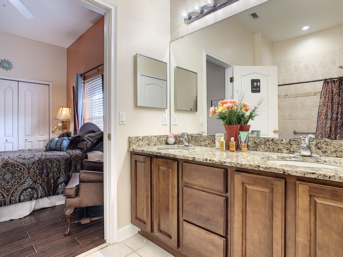 A modern bathroom with a granite countertop and wooden cabinets, featuring decorative flowers on the sink.