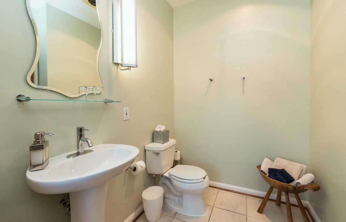 A minimalist bathroom with a sink, toilet, and mirror.