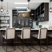 Modern kitchen with a large counter, bar stools, and a wine fridge.