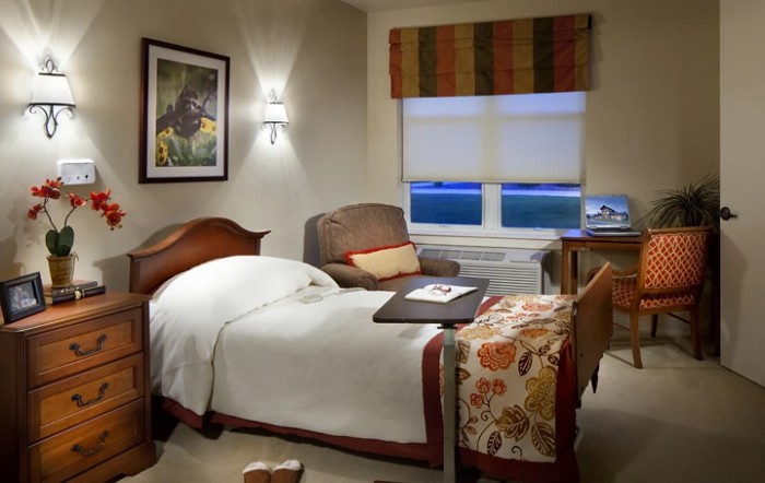 A cozy bedroom with a single bed, armchair, and decorated window.