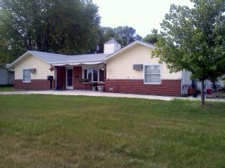 A single-story bungalow with a spacious yard and surrounding trees.