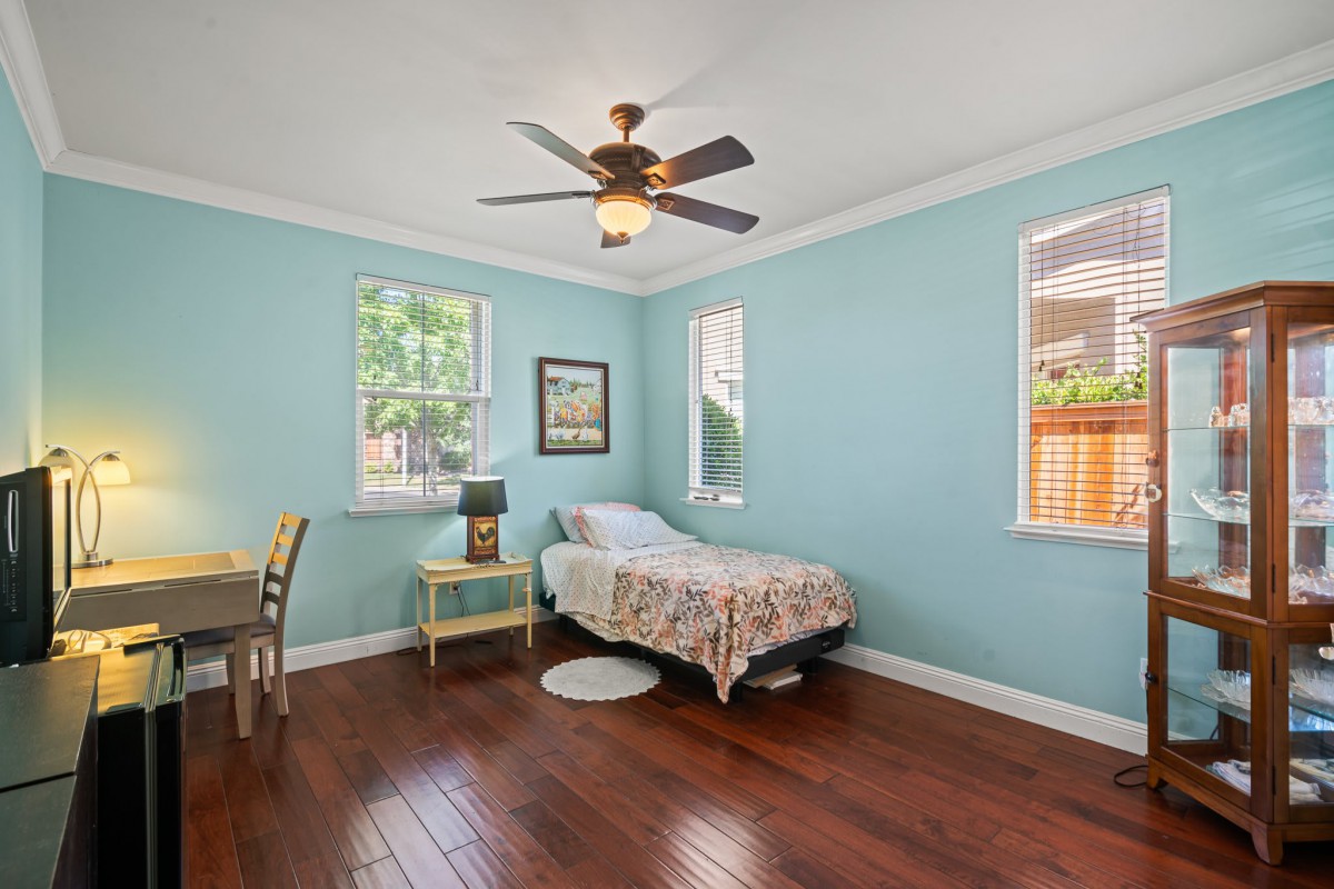 A bright bedroom with blue walls, featuring a single bed and wooden flooring.