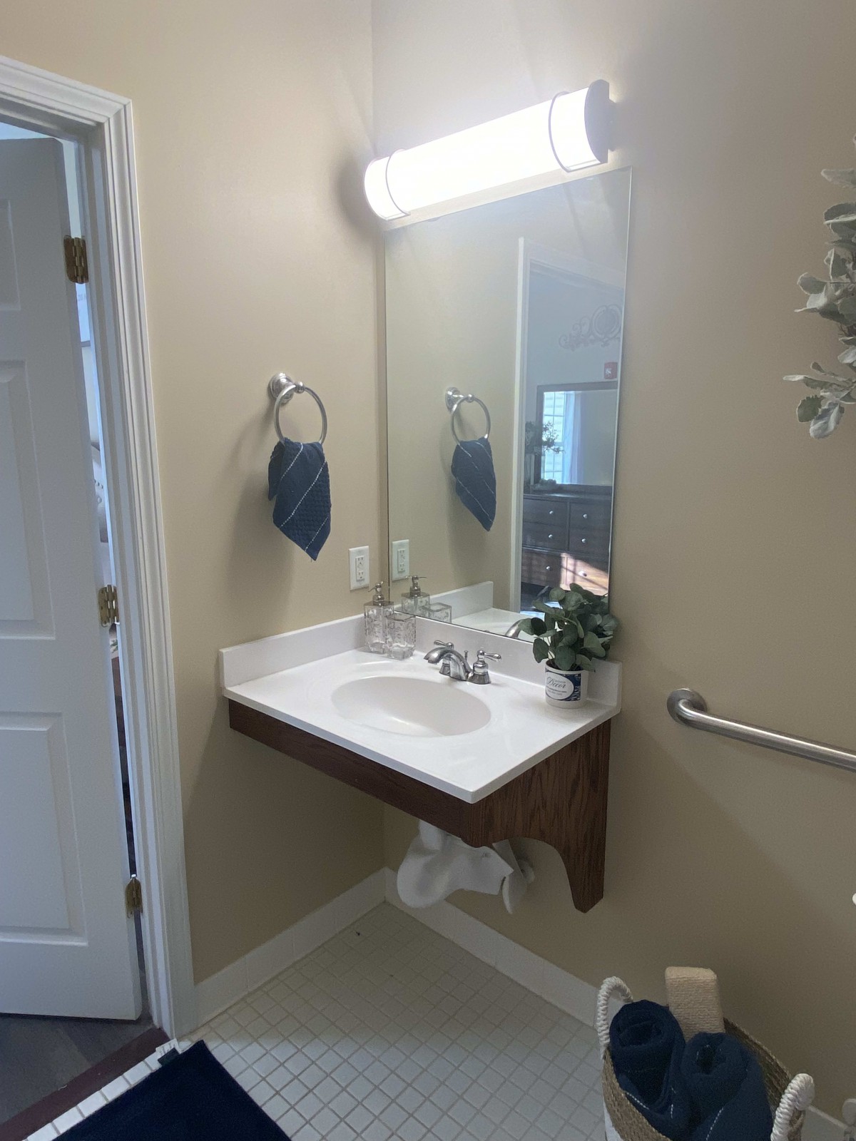 A clean and simple bathroom with a wall-mounted sink, mirror, and light fixture.