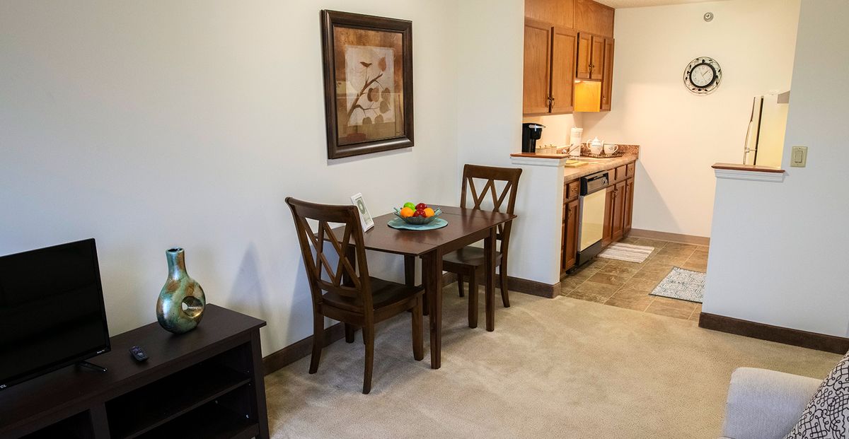 A cozy dining area with a wooden table, two chairs, and a view into the kitchen.