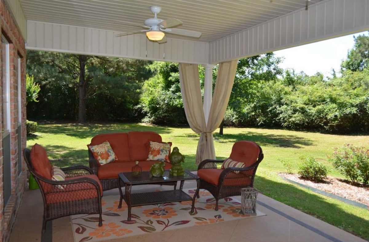 A cozy outdoor patio with comfortable seating overlooking a lush garden.