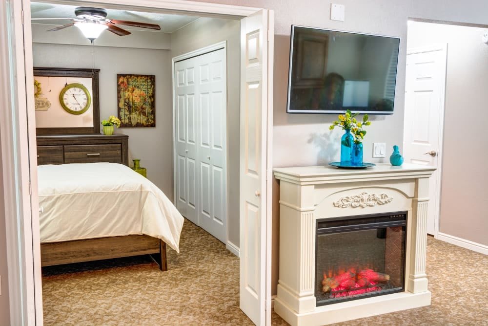 A cozy bedroom featuring a mounted television, electric fireplace, and elegant decor.