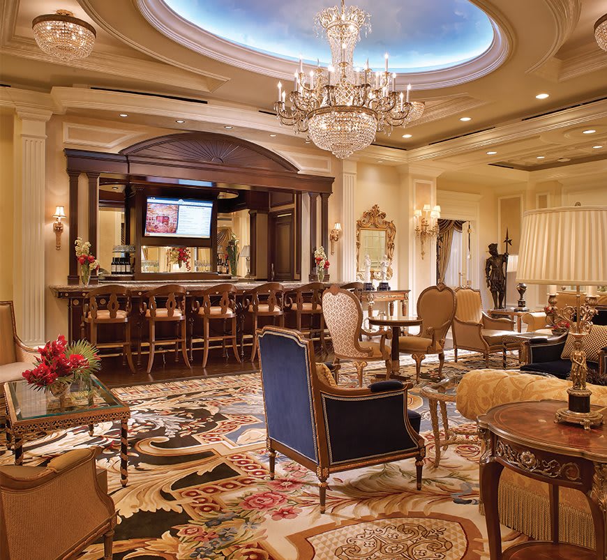 A luxurious bar interior with elegant seating and a grand chandelier.