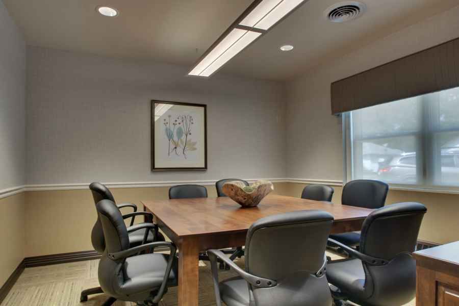 A modern conference room with a wooden table and black chairs.