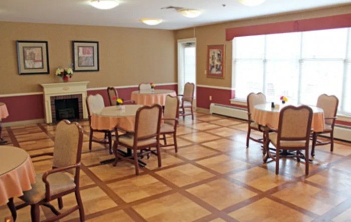 A cozy dining room with neatly arranged tables and chairs, featuring a wooden floor and soft lighting.