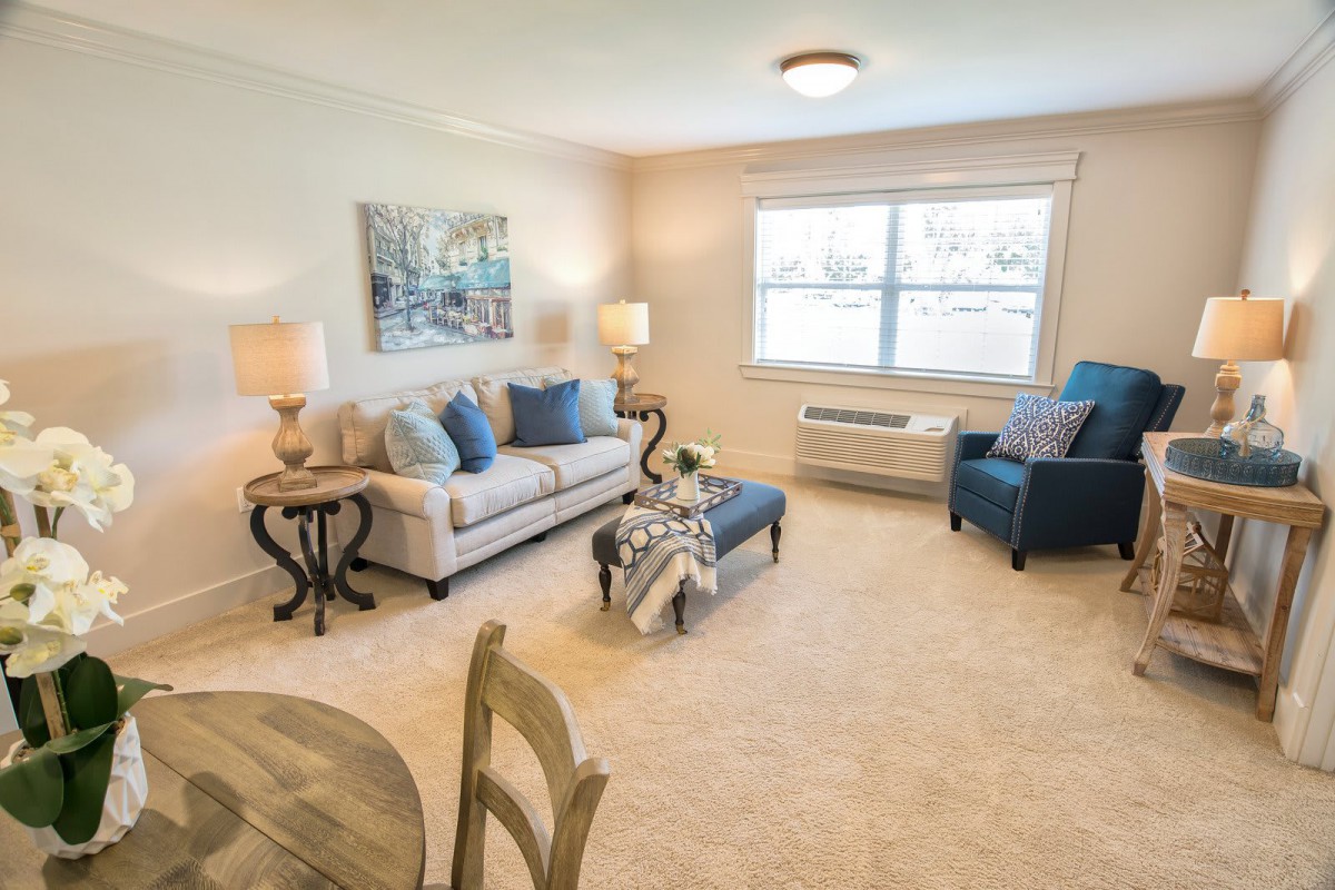 A cozy and well-lit living room featuring a sofa, armchair, and coffee table with neutral tones.
