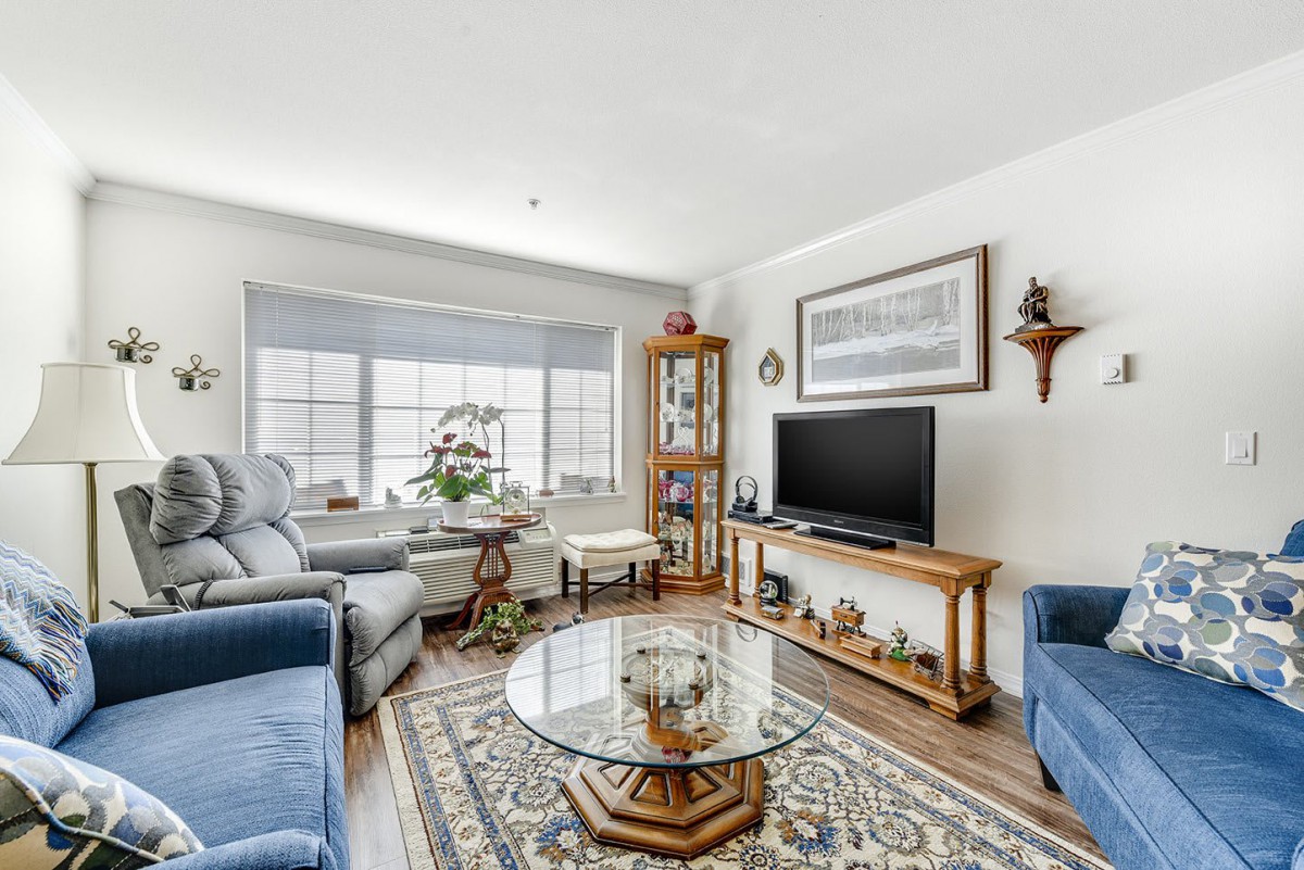 A cozy living room featuring comfortable seating, a glass coffee table, and a TV.