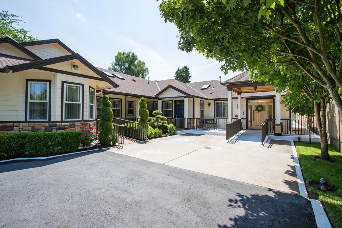 A single-story house with a spacious driveway and surrounding greenery.