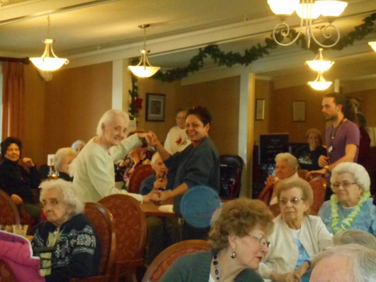 Elderly residents enjoying a dance at a nursing home event.