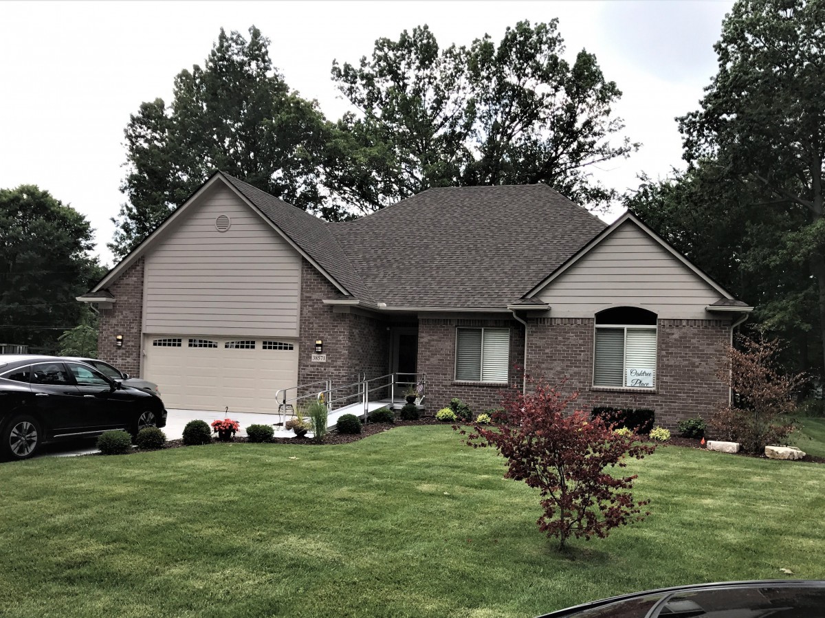 A suburban house with a well-maintained lawn and surrounding trees.